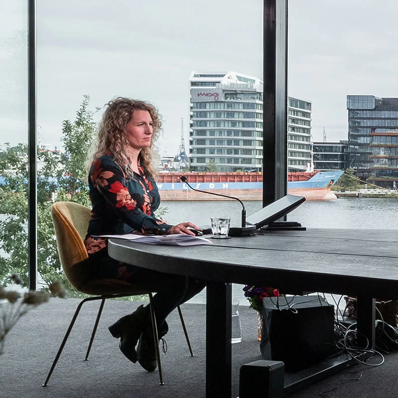 A woman is sitting at a large wooden desk in the professional studio from Crowdale.